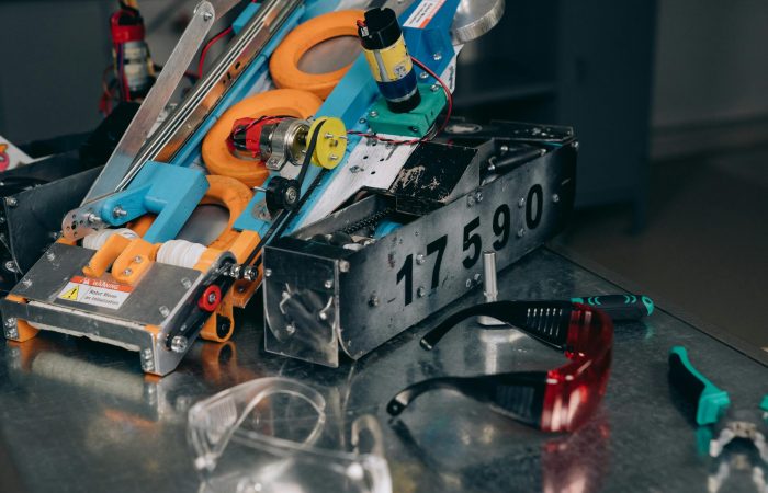 Detailed shot of a robotics machine with safety glasses and tools on metal surface.